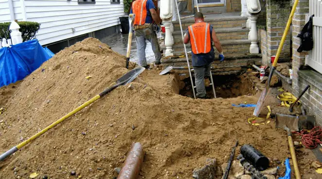 Contractors performing foundation protection and exterior drainage excavation near residential home steps in Arvada, CO